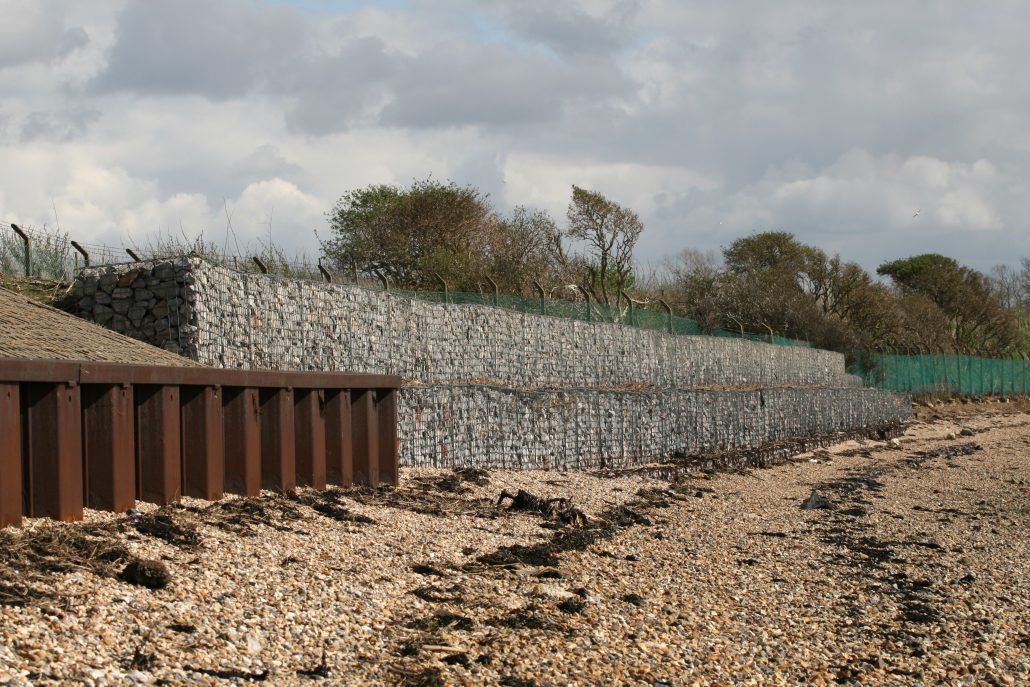 Coastal erosion defences in the form of interlocking concrete blocks in the foreground and stone-filled wired gabion baskets behind