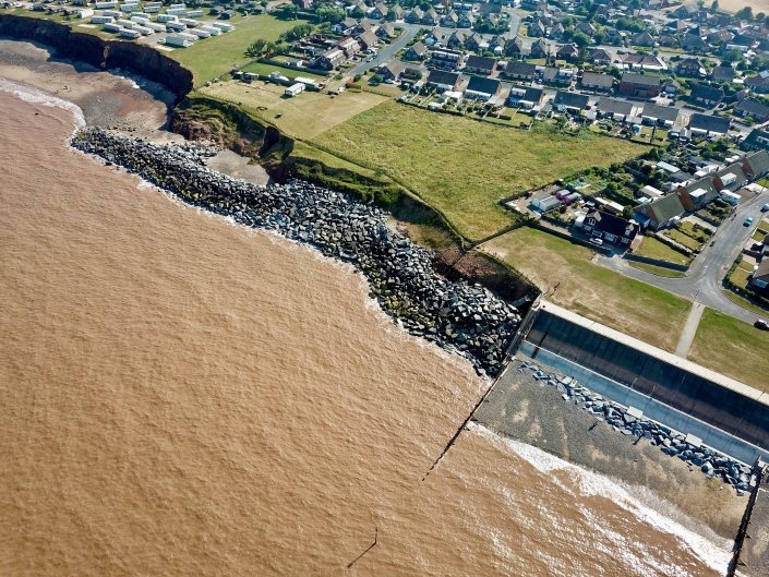 Downdrift of the sea defences at Withernsea , the adjacent undefended coast is being eroded resulting in a set back.