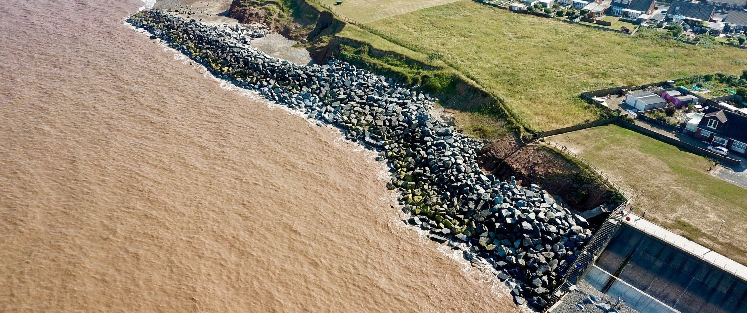Downdrift of the sea defences at Withernsea , the adjacent undefended coast is being eroded resulting in a set back.