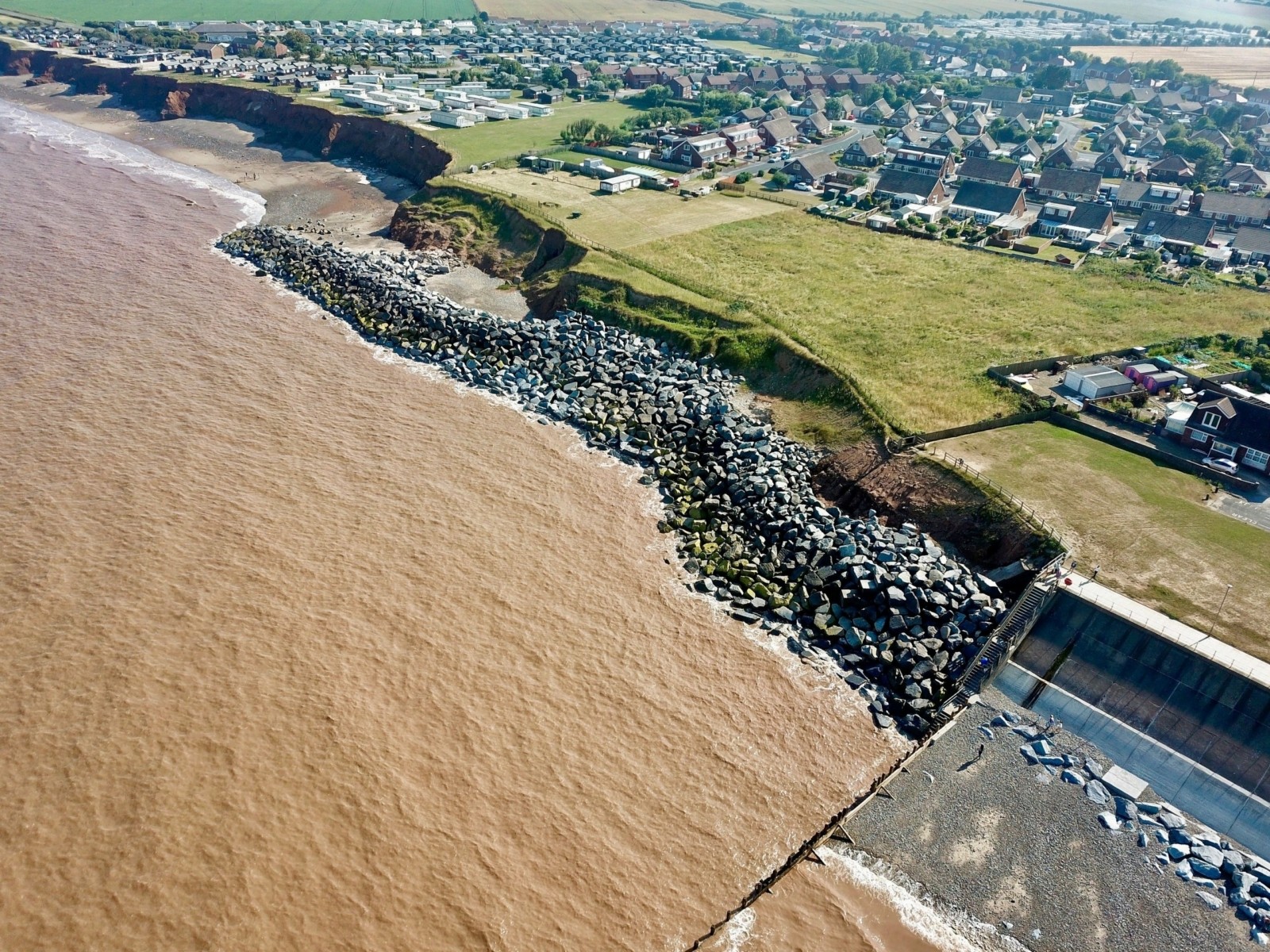 Downdrift of the sea defences at Withernsea , the adjacent undefended coast is being eroded resulting in a set back.