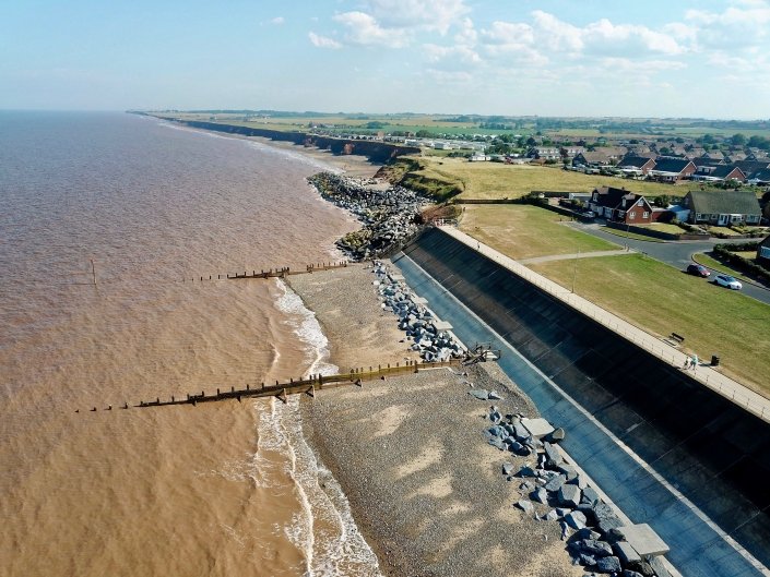 Downdrift of the sea defences at Withernsea , the adjacent undefended coast is being eroded resulting in a set back.