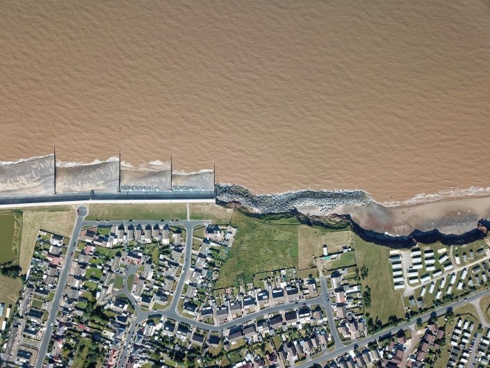 Downdrift of the sea defences at Withernsea , the adjacent undefended coast is being eroded resulting in a set back.