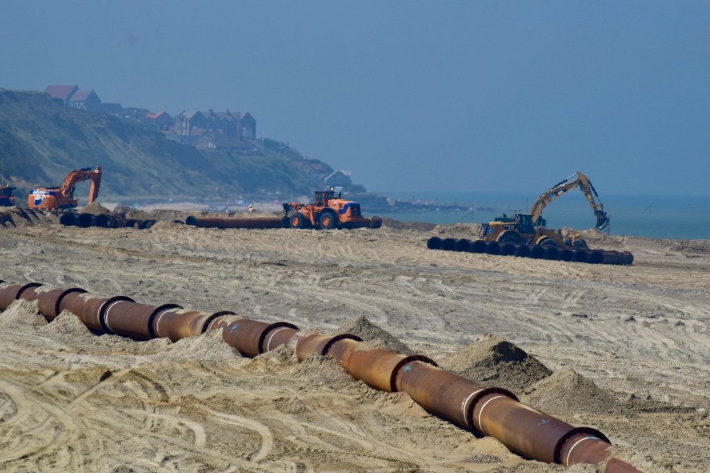 Sediment pumped onto the beach is moved by heavy machinery